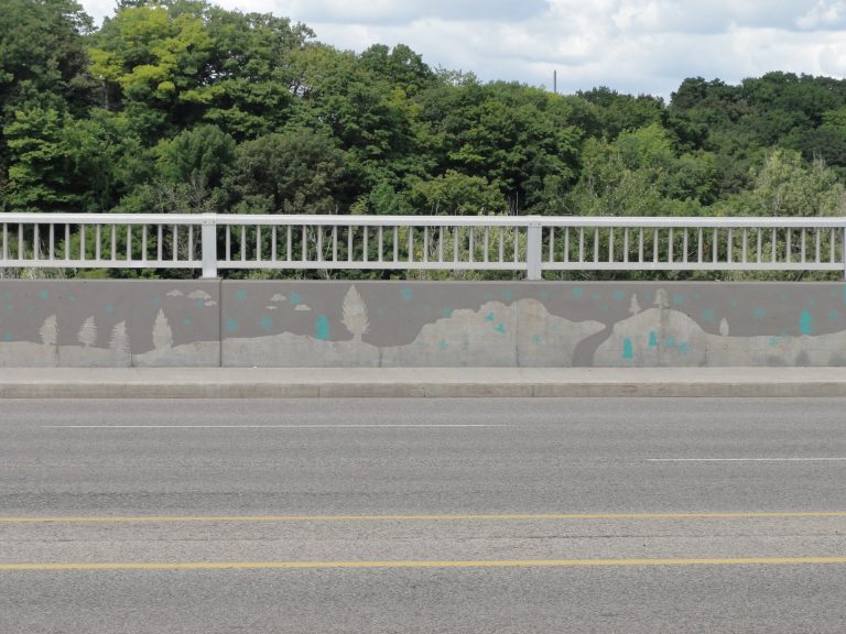 A mural painted on a bridge, depicting silhouettes of trees, clouds and rolling hills in dark gray. Light blue snowflakes, snow men and tobogganers dot the landscape.