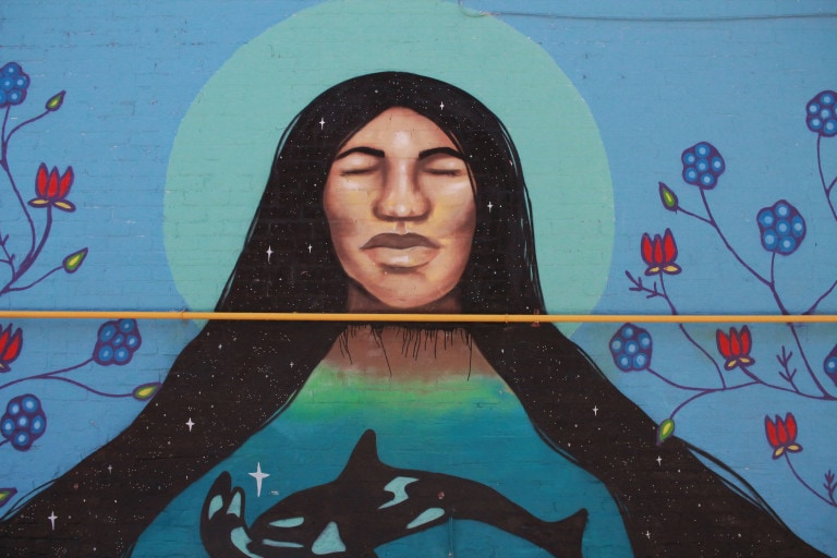 Viewing the focus of the Tahlequah mural (a long-haired figure with a large orca whale holding a smaller orca on its rostum).