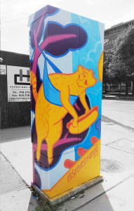 The rear face of the Huron St & Harbord St signal box, featuing a cartoonishly painted raccoon holding a hot dog.