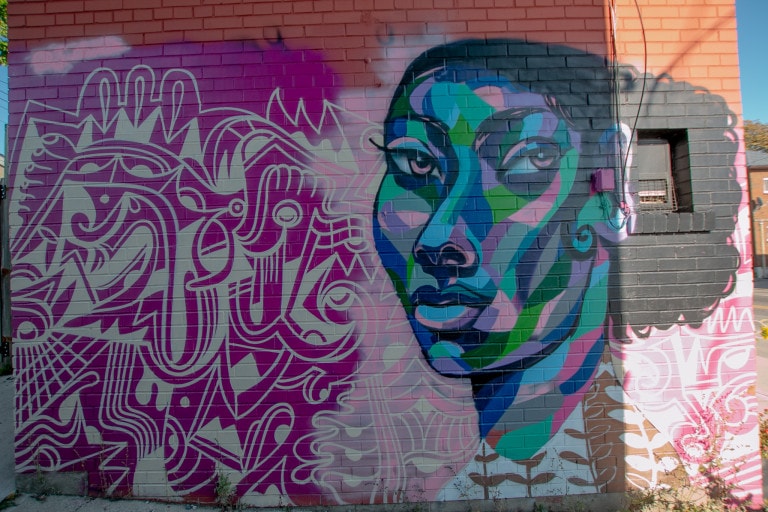 Colourful mural of a character in multi toned colour blocks and a purple abstract illustrative background