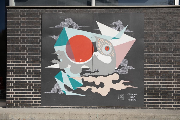 Black panel with a grey, bird figure in the centre. The bird's shape mimics the clouds in the background of the image. Between the bird and clouds are shapes that resemble origami folds, one shades of teal and one white and pink. Just above the bird is a large, red circle.