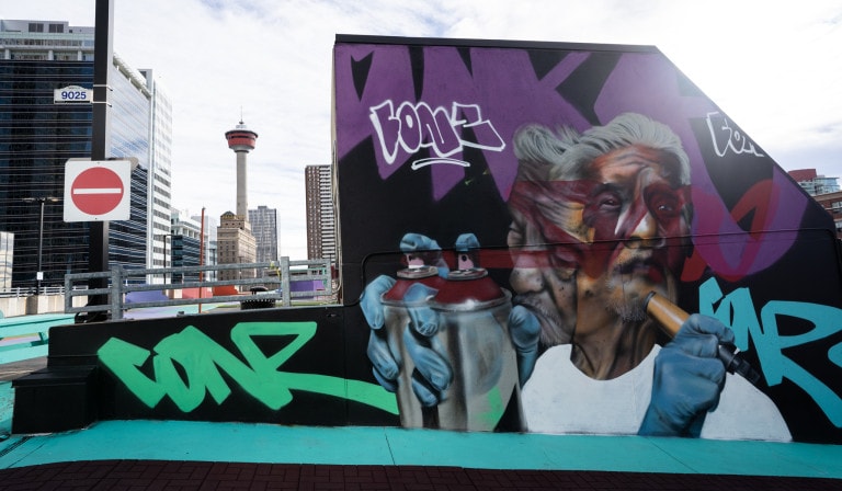 Movement of a portrait of a man holding a spray paint can and marker. Tagged lettering and graffiti surround the portrait.