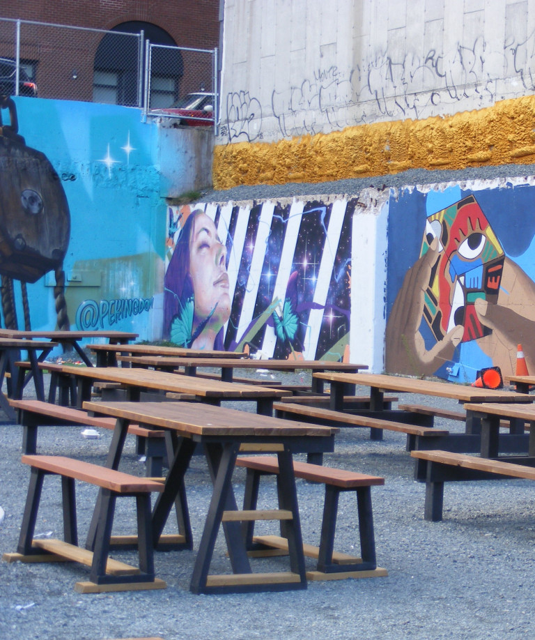 A woman, set against black and white stripes, closes her eyes and tips her head back. There are other murals to the left and right of this one.