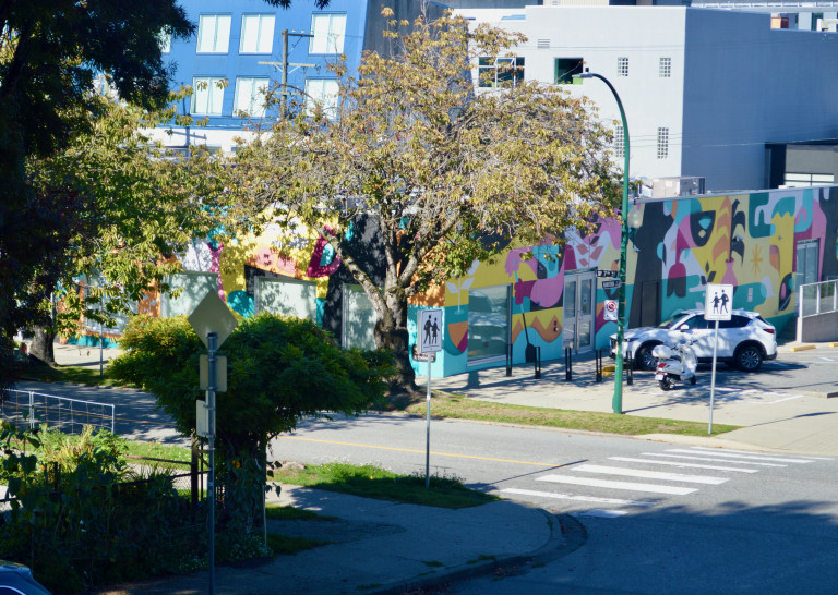 Above eye level street view of building hosting mural on multiple walls