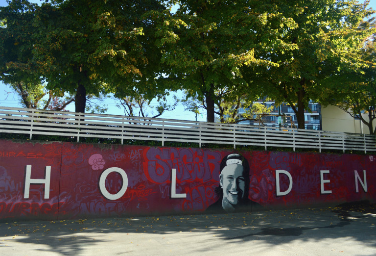 Red and blue long horizontal wall mural with white lettering reading Holden, and a portrait between the L and D