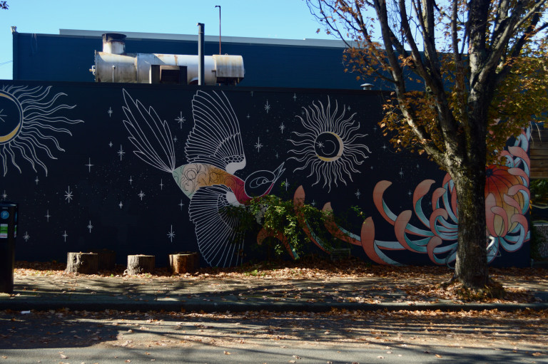 Large wall with a bird in flight approaching a chrysanthemum against a dark sky