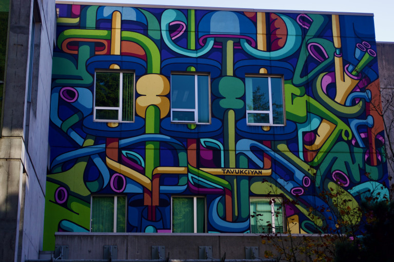 Colourful abstract shapes in cool tones cover the wall of a university building.