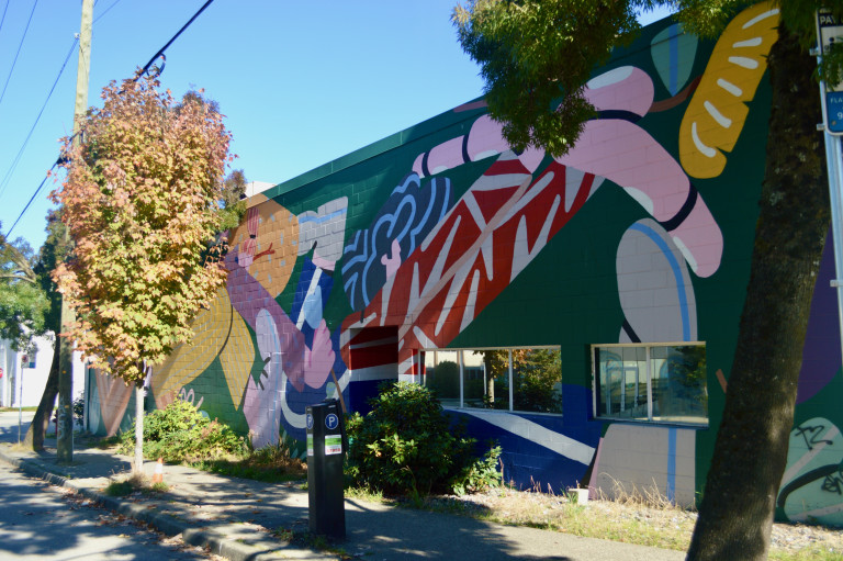 A large colourful pop art mural featuring a clown picking a flower to smell