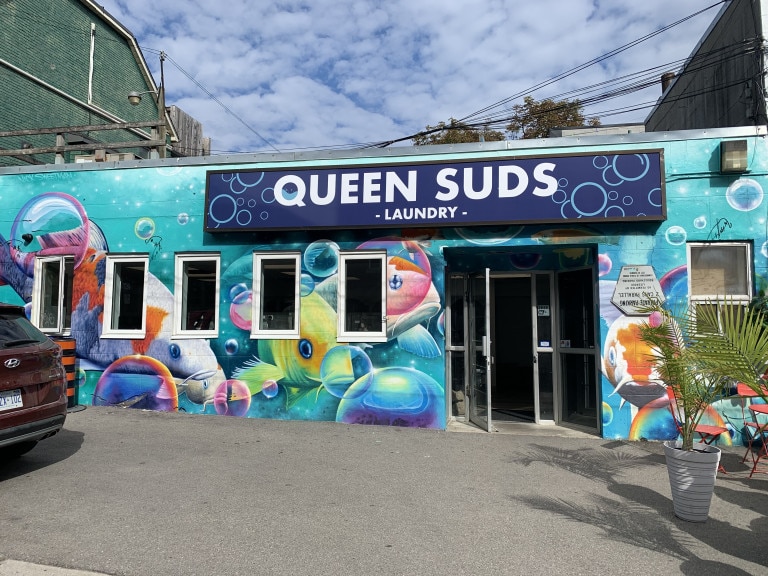 Photo of a storefront mural for Queen Suds Laundry of multiple colourful fish swimming in an ocean of bubbles.