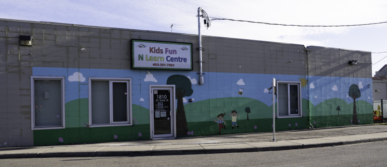 Girl and boy figure playing the middle of mural with tree on left side. Bee flying on right. Hills and blue skies in background.