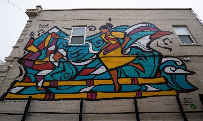 From left to right. Bboy breakdancing and woman figure dancing. Abstract imagery of mountain and bird in background. Music notes flowing around.