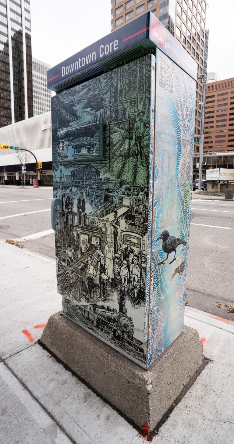 'Eau Claire Bow River Lumber Co.' text on lower center of utliity box with workers around and trees/forest at top. Raven on side of utility box.