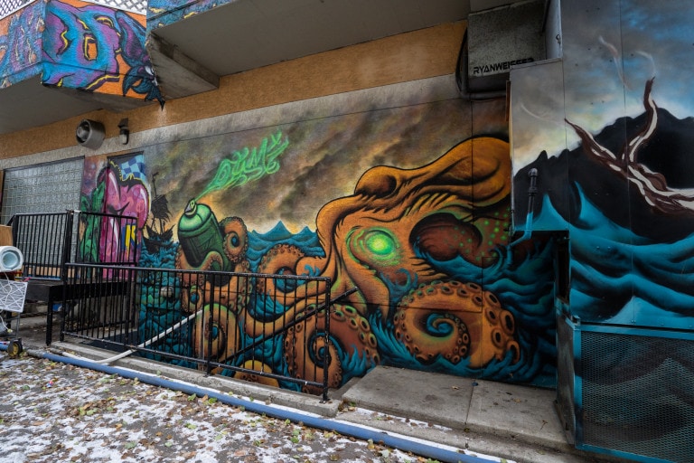 Giant octopus holding a spray paint can in one tentacle in a body of water.