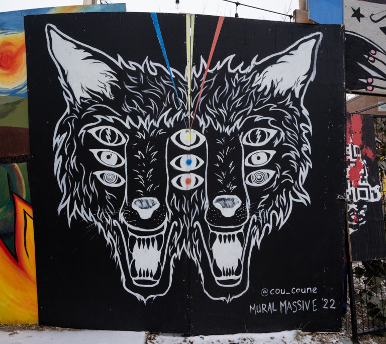 Two faces of wolves merged on each side 3 sets of eyes each. Top eye pupil is yellow, middle pupil is blue and bottom pupil is red. Lazers from each coloured pupil shooting upwards.