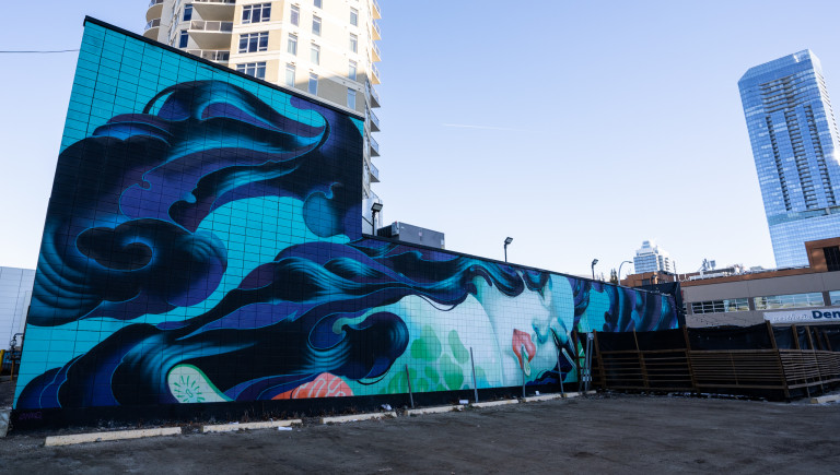 Bluish-green mermaid with flowing hair eating a cucumber slice.