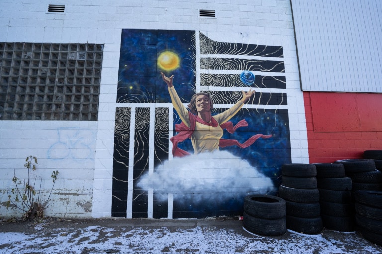 Lady figure with cloud as legs holding sun in one hand and earth in the other. Galactic space-like background and colours.