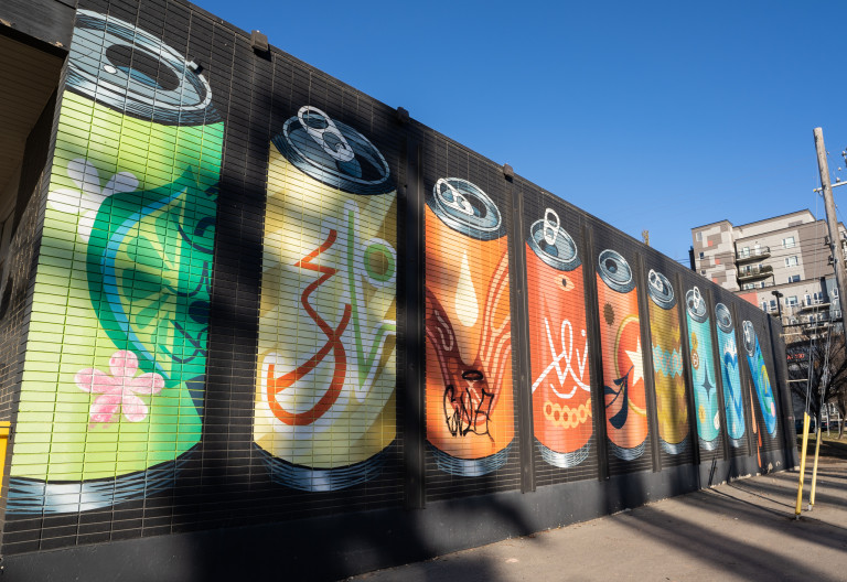 Soda pop cans of different designs, all same sizes, with space in between each one lined up.