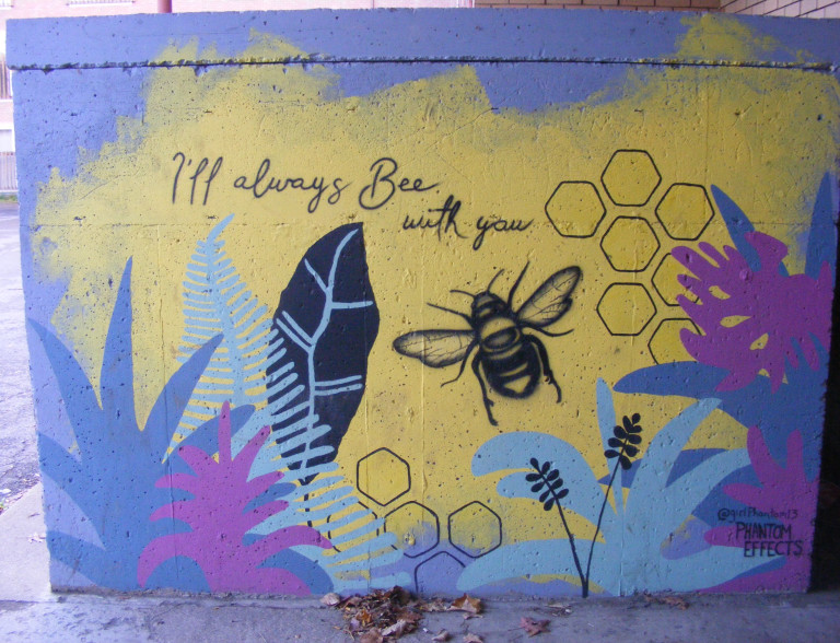 A bee flies around flowers, leaves, plants and honeycombs. "I'll always bee with you" is written above the bee.