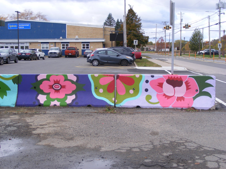 Barricades in a parking lot are painted with ornate, folksy flowers.